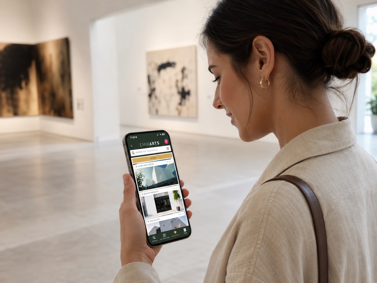 A visitor in a gallery browsing the EMIRARTS app on her phone